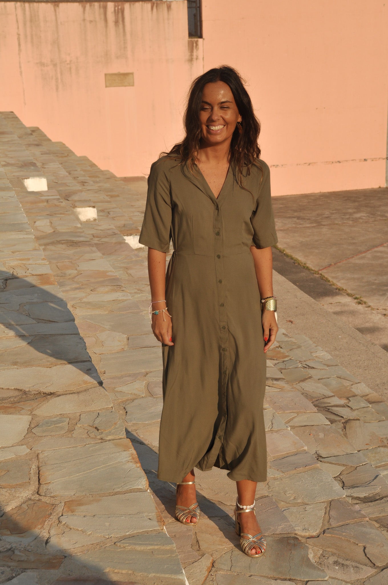 Vue de côté d'une robe longue kaki fluide : fente latérale discrète visible.