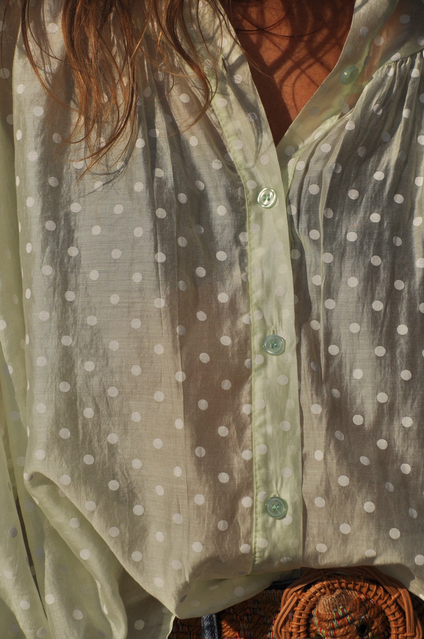 Gros plan sur le tissu en voile léger vert pastel à pois et les boutons de la blouse