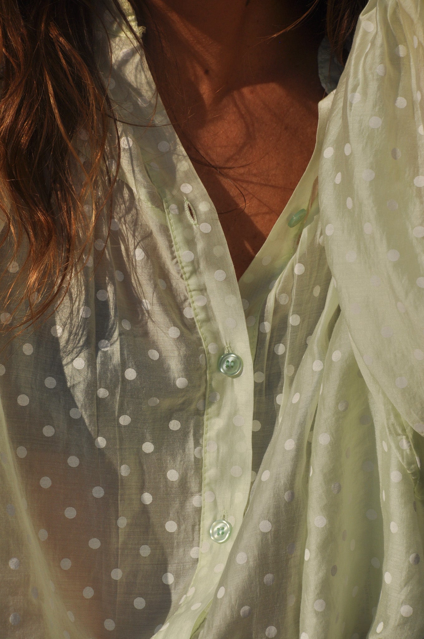 Détail de la texture légère et des fronces de la blouse à pois vert pastel