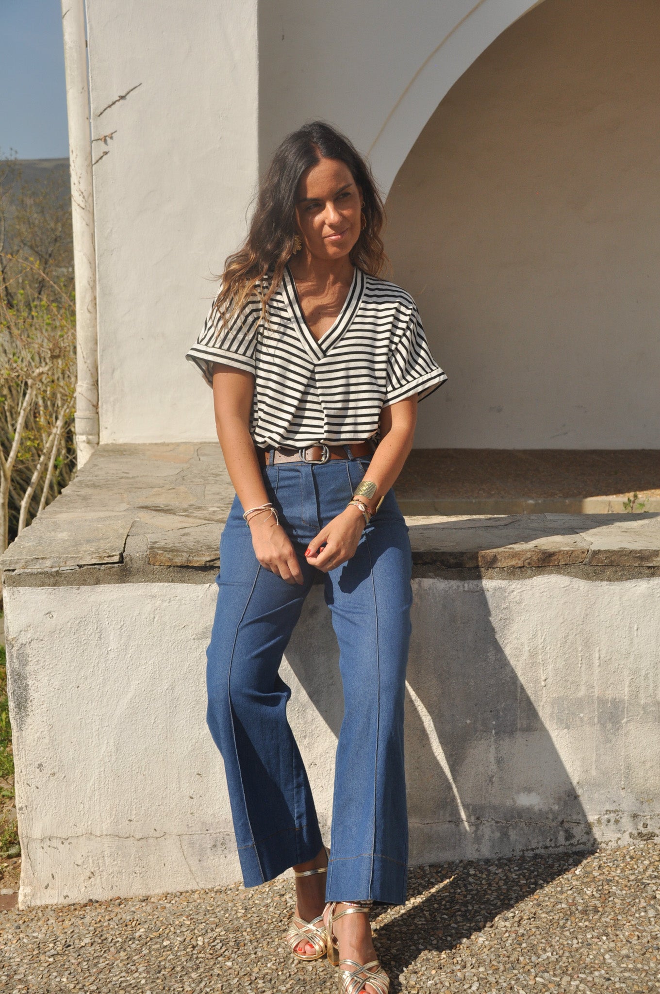 Femme assise portant un pantalon large en jean bleu à surpiqûres verticales sur le devant