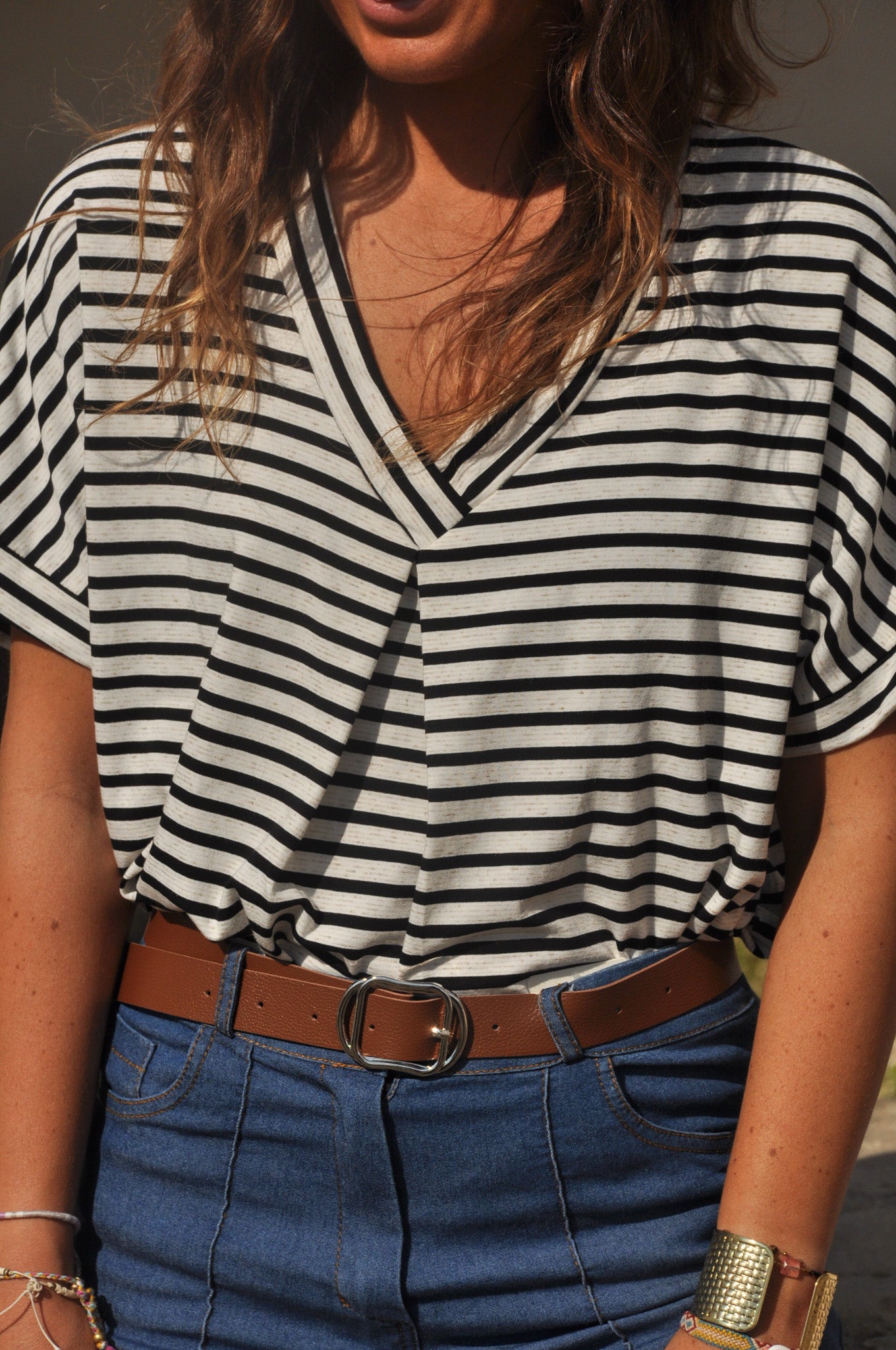 Gros plan sur l'encolure en V d'un t-shirt femme en maille légère à fines rayures noires et écrues