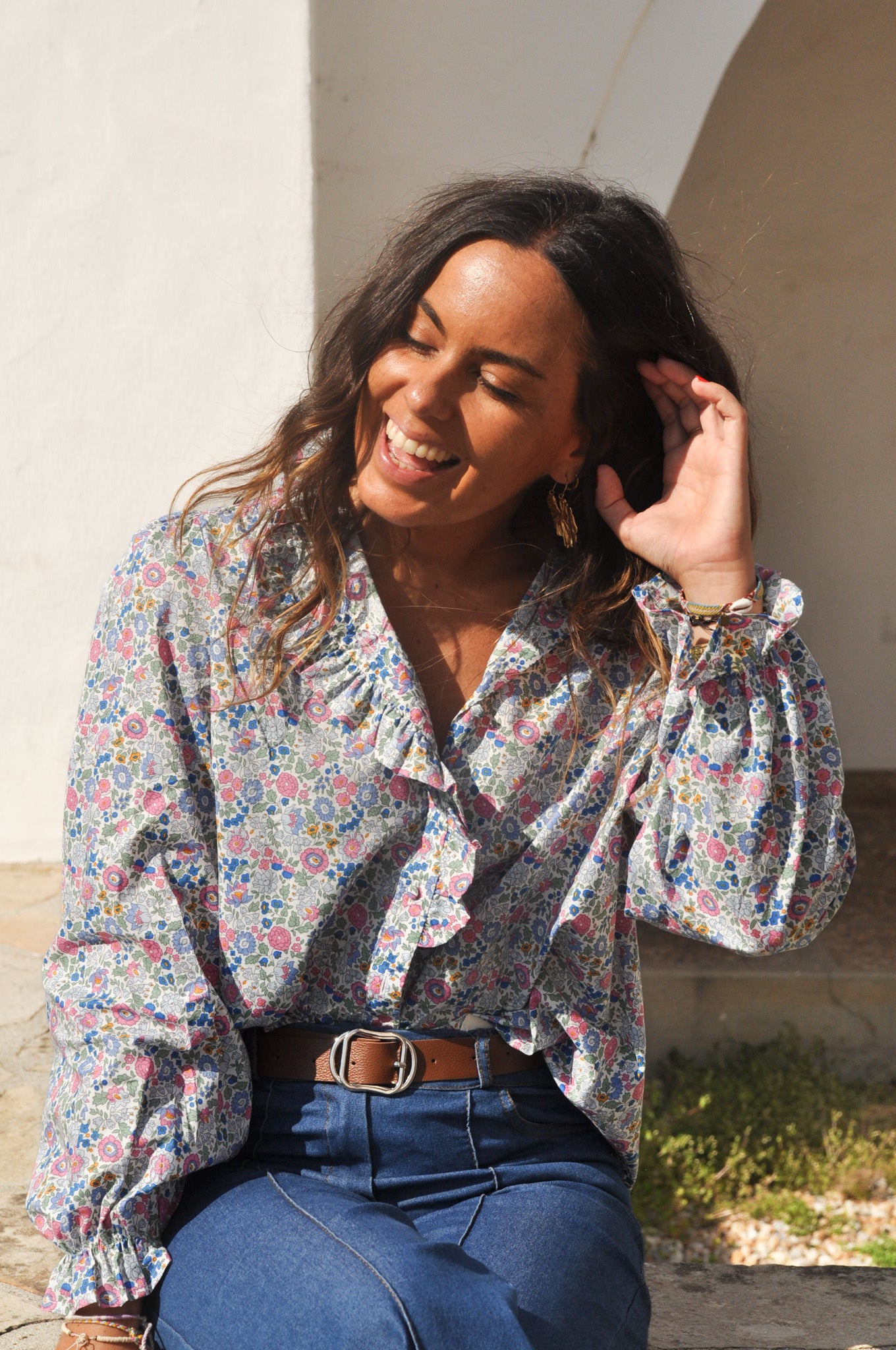 Femme portant une blouse blanche bohème avec broderies et un pantalon large en jean bleu clair fluide