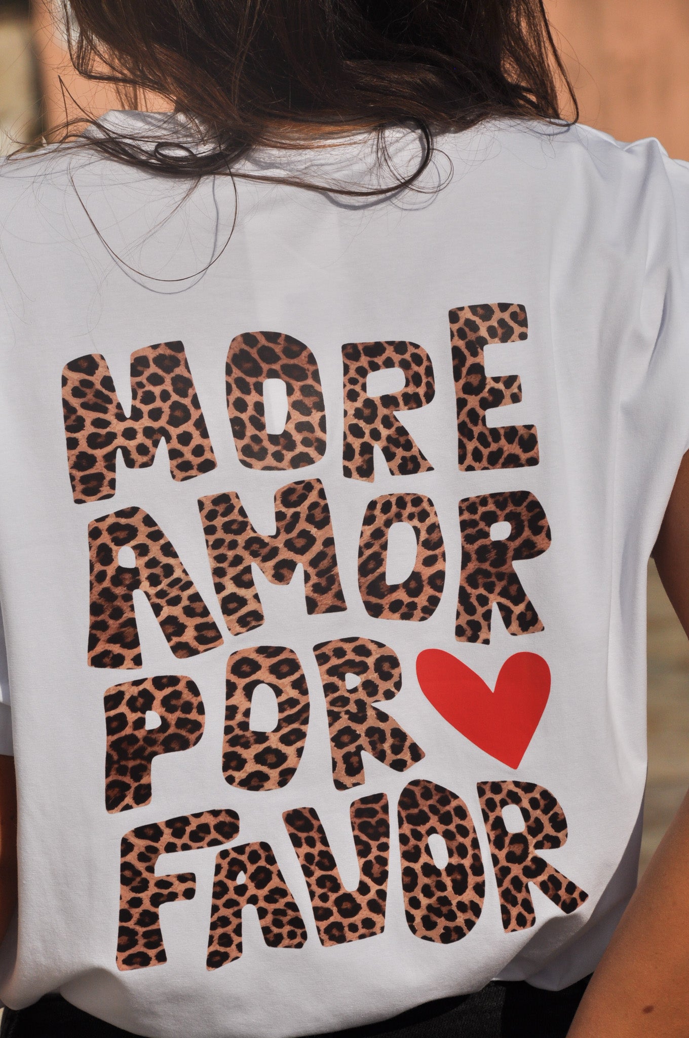 Gros plan sur le dos d'un t-shirt blanc femme avec grand imprimé léopard 'More Amor Por Favor' et cœur rouge.